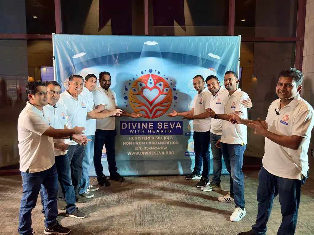 Divine Seva volunteers gathered around the organization banner at a Los Angeles event